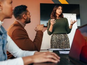 Female manager giving a presentation in a boardroom. Young businesswoman presenting her business strategy to her colleagues. Group of multiracial entrepreneurs having a meting in a modern office.