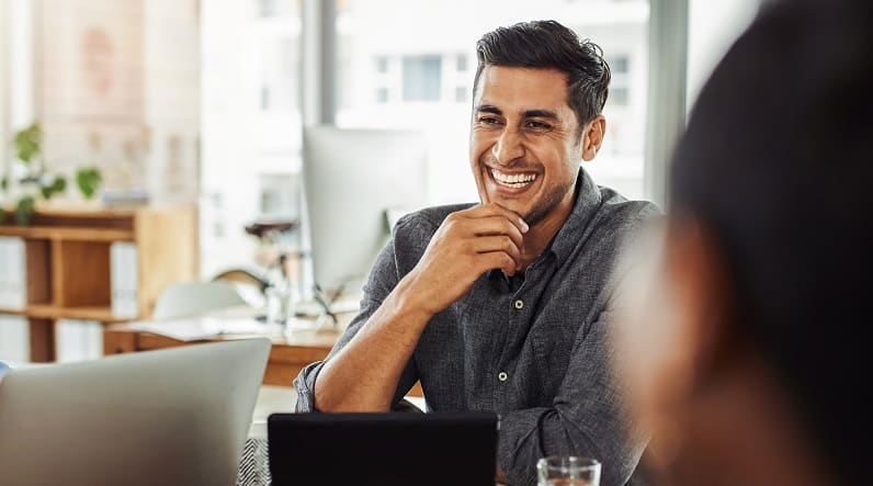 Shot of a young businessman smiling during a meeting with colleagues at work