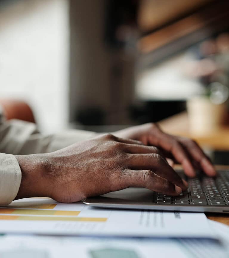 A close up of mans hands typing on his laptop