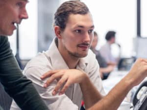 Two male colleagues discuss work at a laptop