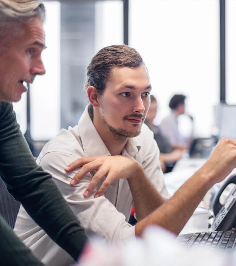 Two male colleagues discuss work at a laptop